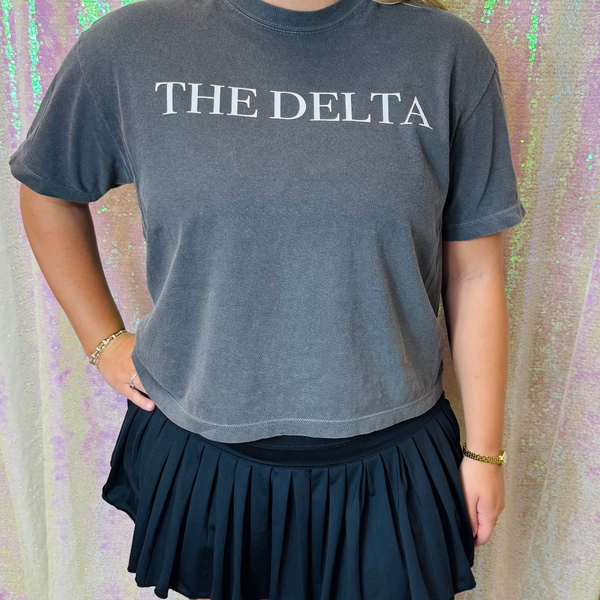 Person wearing a gray t-shirt with 'THE DELTA' text against a colorful, patterned background