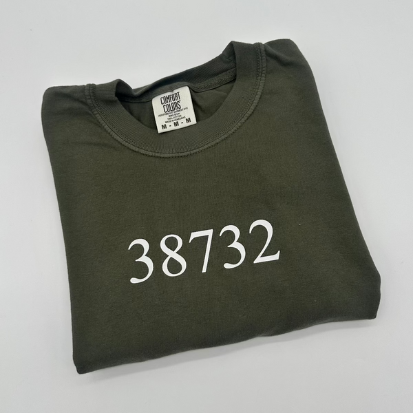Folded green sweatshirt with '38732' printed on it against a light gray background